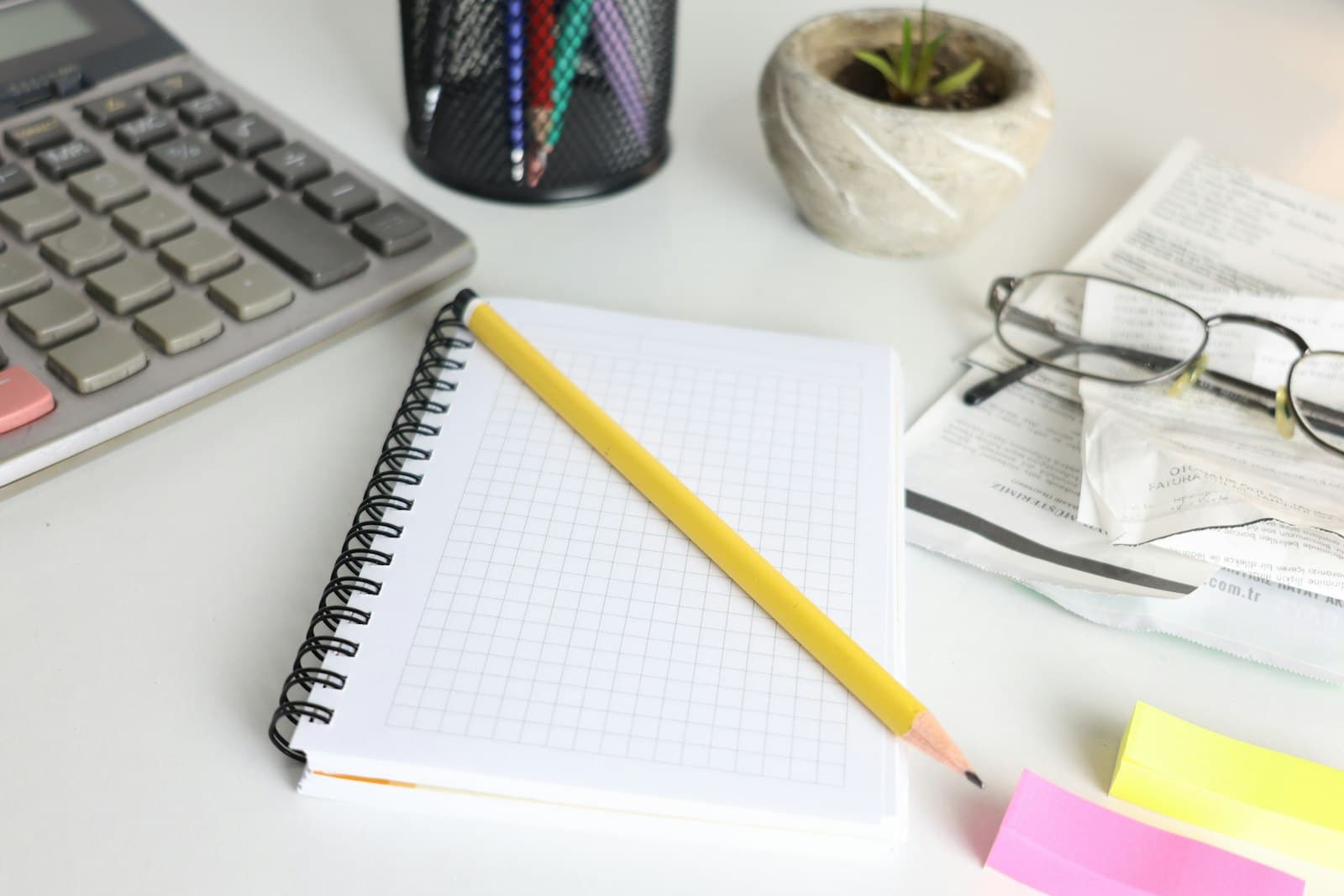 Calculator, notebook and reading glasses on a desk
