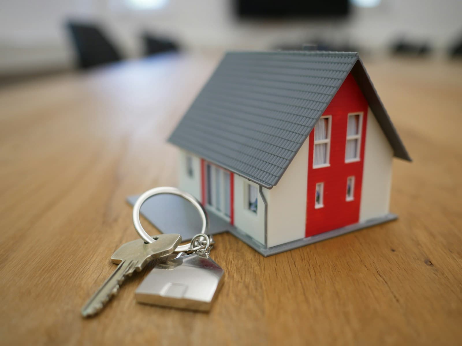 Model house and keys on a wooden table.