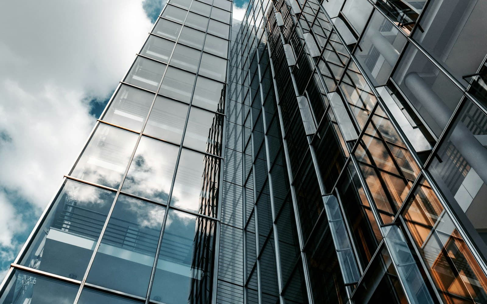 Reflective glass office façades against a clouded sky.