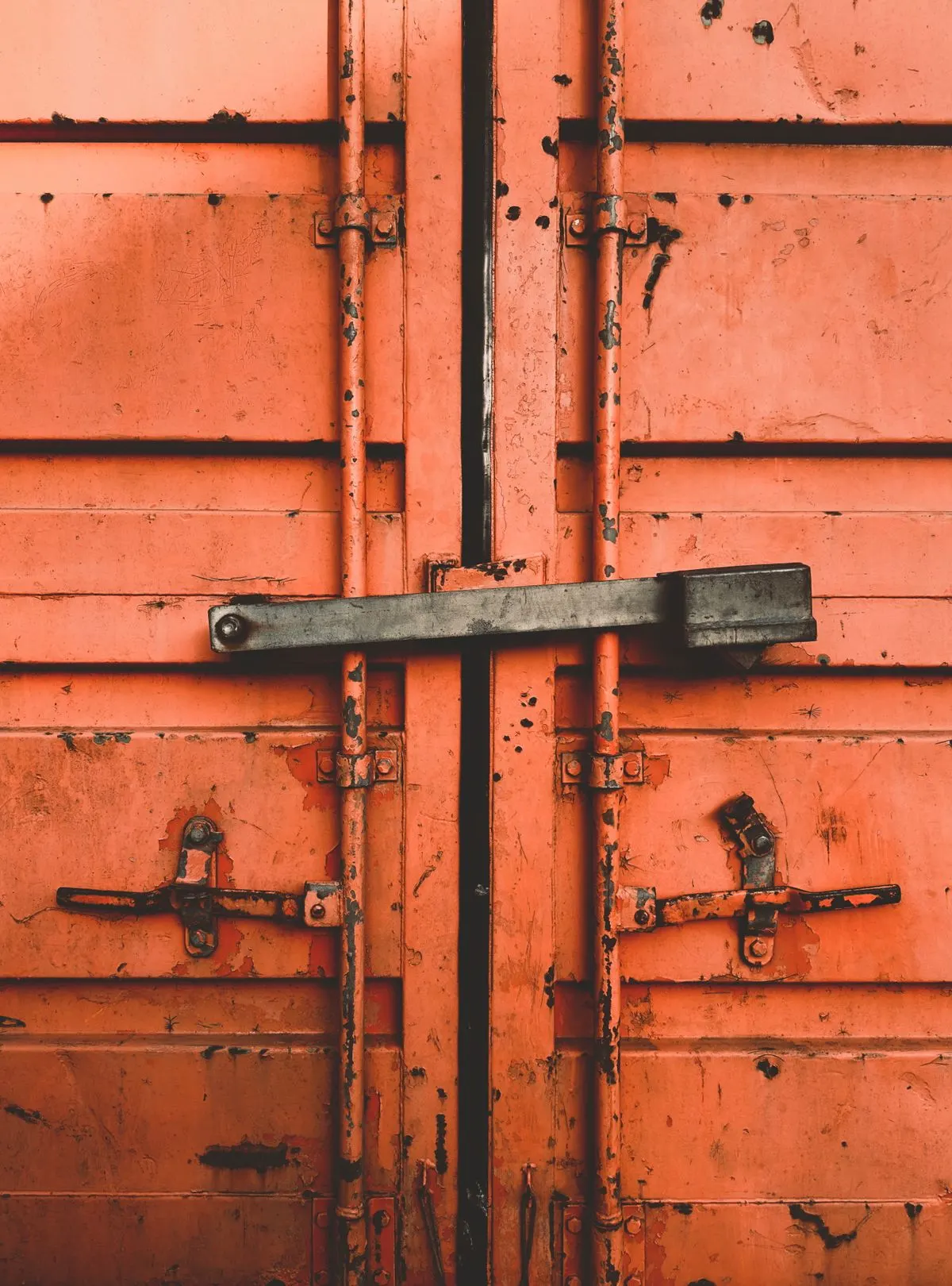 Close-up of secured orange shipping-container doors.