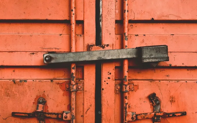 Close-up of secured orange shipping-container doors.